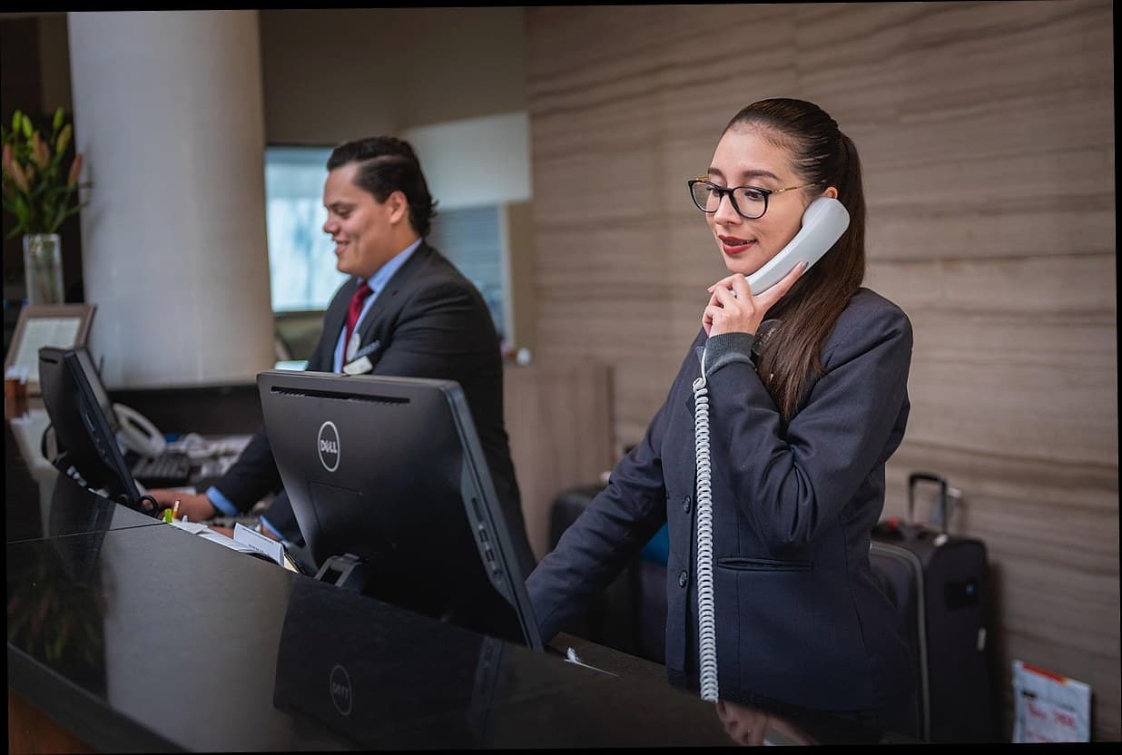 Resepsionis klinik kecantikan melayani pelanggan dengan senyum di meja counter modern