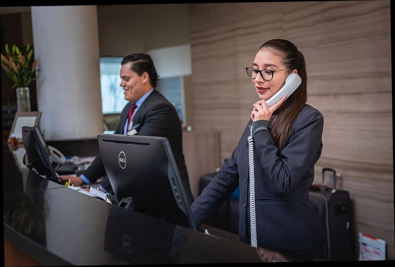 Pasien wanita senang di klinik kecantikan dengan staf resepsionis