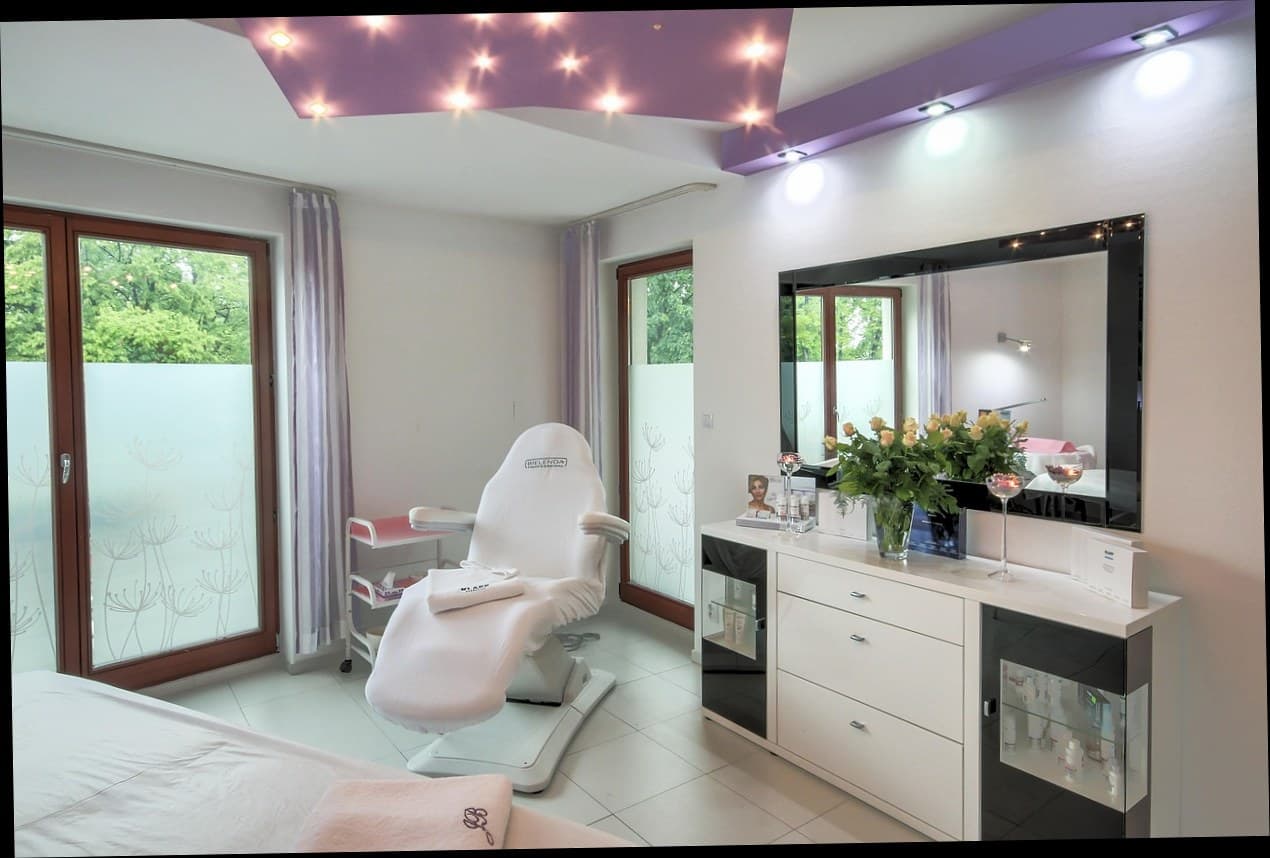 Interior klinik kecantikan modern dengan resepsionis dan pelanggan yang menggunakan aplikasi mobile.